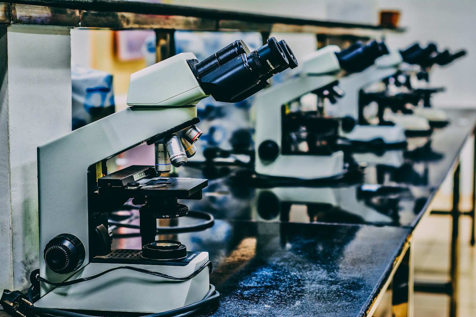 A row of laboratory microscopes on a bench, representing medical laboratory examination equipment