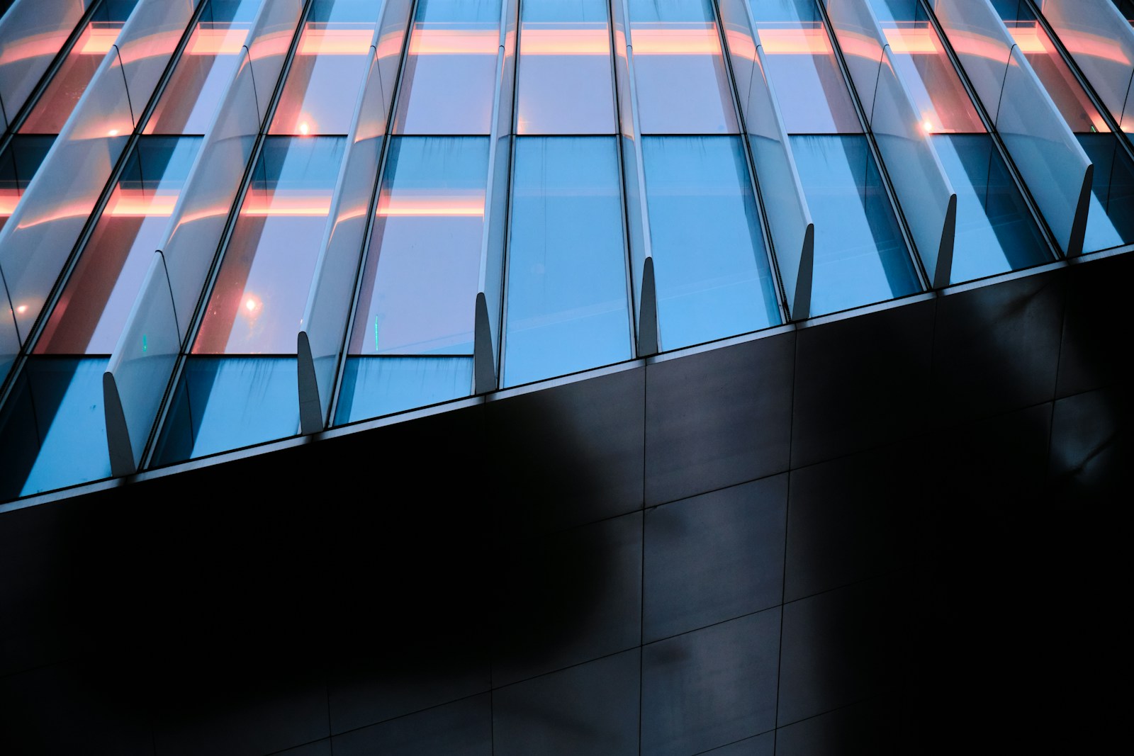 Abstract close-up of a modern glass and steel office building facade at dusk, representing structured quality management