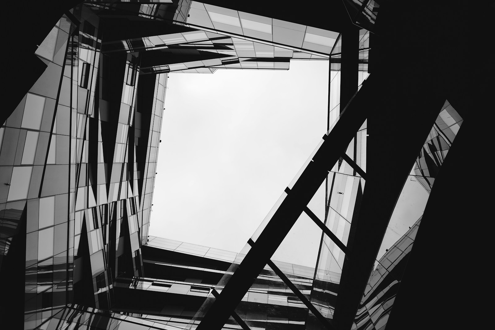 Dramatic upward view of modern glass architecture in sharp black and white geometric lines, evoking the precision and structure of an ISO-certified management system